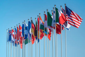 Picture of flags of several different countries against a cloudless blue sky
